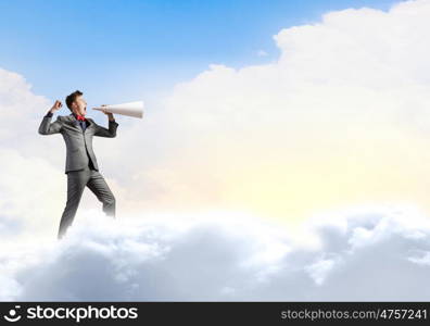 Man with trumpet. Young businessman screaming emotionally in paper trumpet