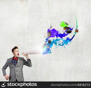 Man with trumpet. Young businessman screaming emotionally in paper trumpet