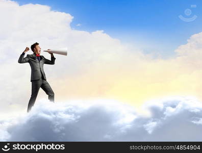 Man with trumpet. Young businessman screaming emotionally in paper trumpet