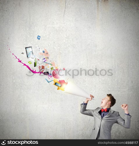 Man with trumpet. Young businessman screaming emotionally in paper trumpet