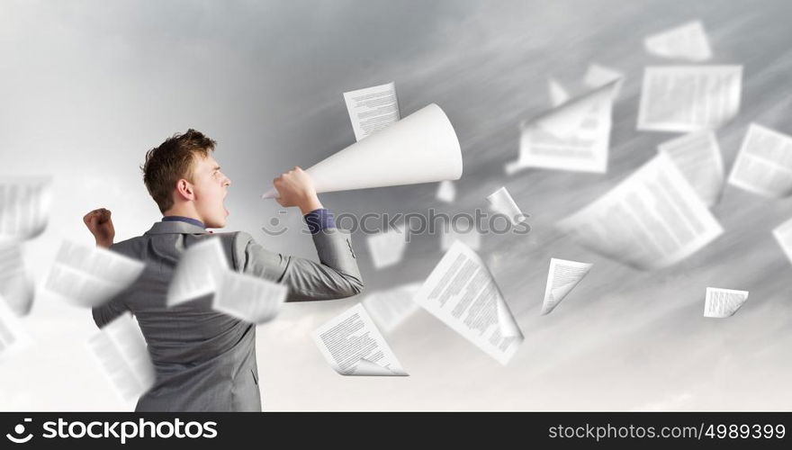 Man with trumpet. Young businessman screaming emotionally in paper trumpet