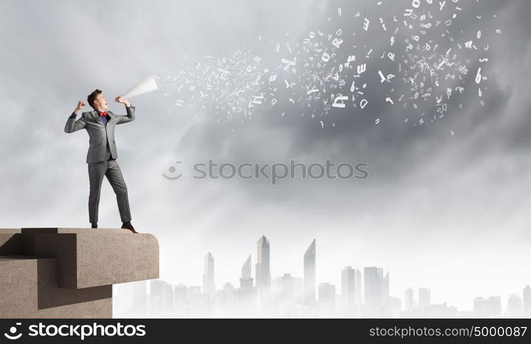 Man with trumpet. Young businessman screaming emotionally in paper trumpet