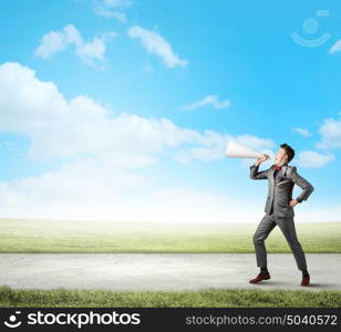 Man with trumpet. Young businessman screaming emotionally in paper trumpet