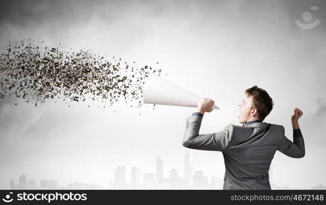 Man with trumpet. Young excited businessman screaming in paper trumpet