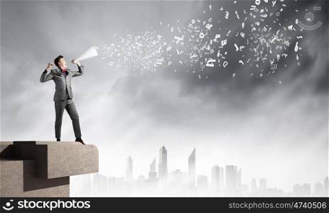 Man with trumpet. Young excited businessman screaming in paper trumpet