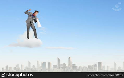 Man with trumpet. Young excited businessman screaming in paper trumpet