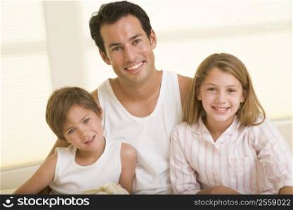 Man with two young children sitting in bed smiling
