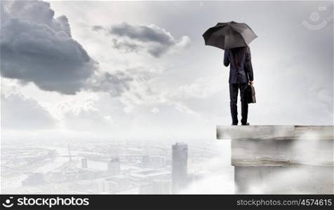 Man with umbrella. Young handsome businessman on top of building with umbrella
