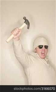 Man with wool sweater and wool hat holds up a hammer in sign of strength