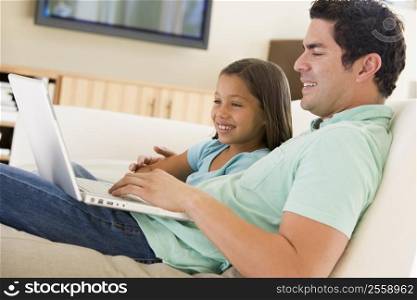 Man with young girl in living room with laptop smiling