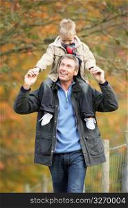 Man With Young Son On Shoulders Autumn Park