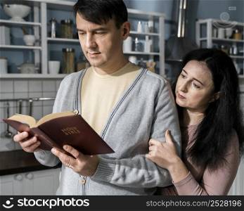 man woman kitchen reading from bible