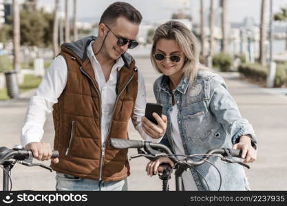 man woman looking phone their bikes