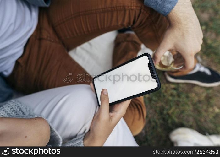 man woman looking phone while having picnic outside