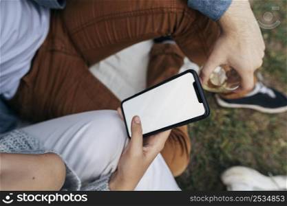 man woman looking phone while having picnic outside