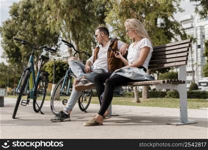man woman sitting bench their bikes