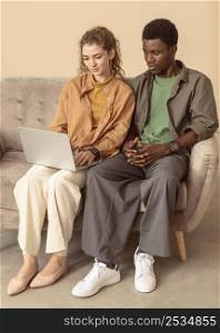 man woman sitting couch using laptop