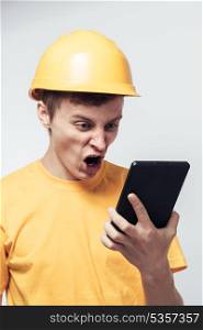 Man worker in a helmet stares at tablet pc