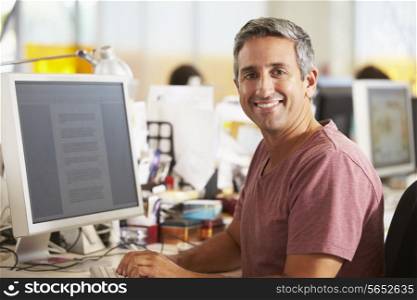 Man Working At Desk In Busy Creative Office