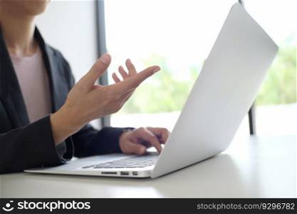 Man working by using a laptop computer on wooden table. Hands typing on a keyboard.