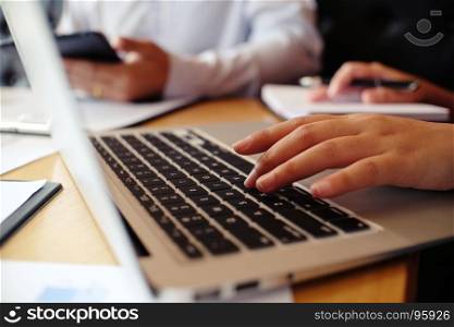 Man working by using a laptop computer on wooden table. Hands typing on a keyboard.