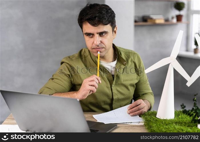 man working eco friendly wind power project thinking while holding pencil