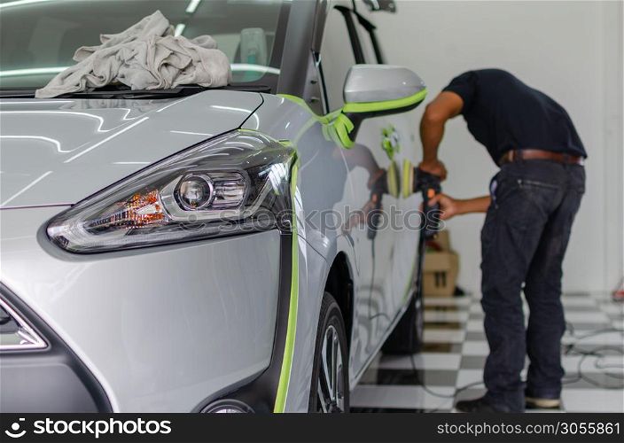 Man working for polishing, coating cars. polishing of the car will help eliminate contaminants on the surface of the car.Waxing the car surface will cause shine after polishing the car. Focus on the car headlights