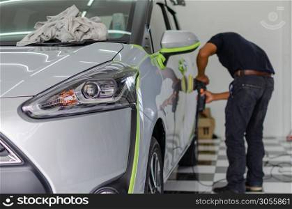 Man working for polishing, coating cars. polishing of the car will help eliminate contaminants on the surface of the car.Waxing the car surface will cause shine after polishing the car. Focus on the car headlights