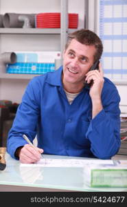 Man working in a plumber&rsquo;s merchants on the telephone