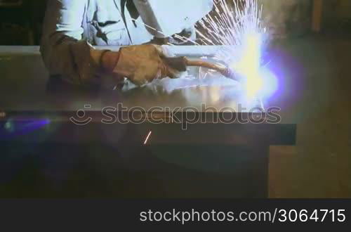 Man working in industry using welding mask, tools and equipment on metal