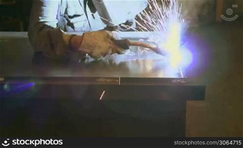 Man working in industry using welding mask, tools and equipment on metal