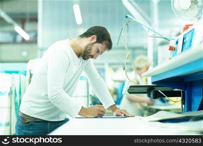 Man working in launderette making notes