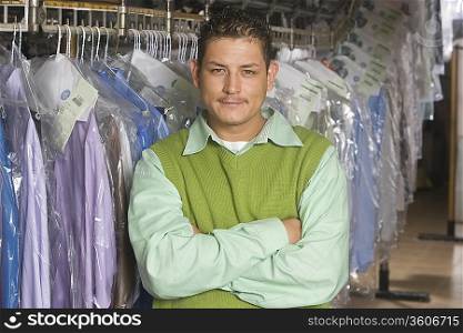 Man working in the laundrette standing infront of clothes rail