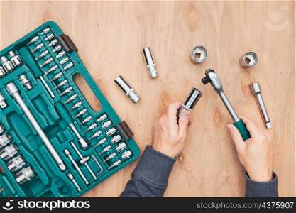 Man working in workshop using many tools. Wrench, spanner, calliper and ratchet with many attachments. Work tools. Universal tool set. Professional equipment