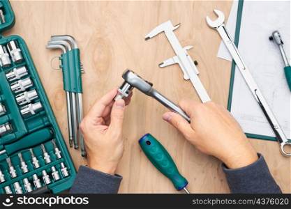 Man working in workshop using many tools. Wrench, spanner, calliper and ratchet with many attachments. Work tools. Universal tool set. Professional equipment