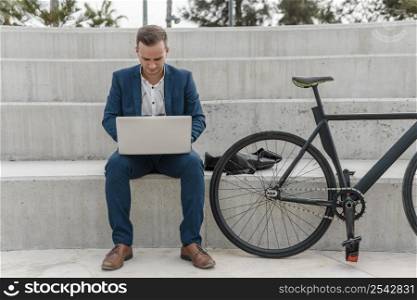 man working laptop his bike outside