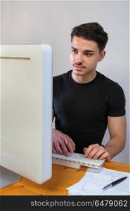man working on computer. a young man with black tshirt working on the computer