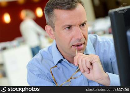Man working on computer, arm of spectables in his mouth