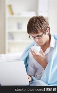 Man working on his laptop with a blanket