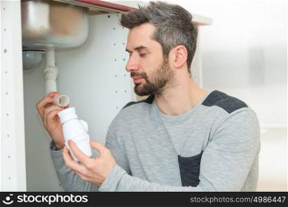 man working on kitchen sink siphon