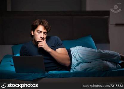 Man working on laptop at night in bed