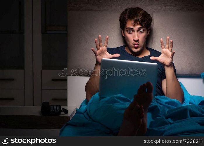 Man working on laptop at night in bed