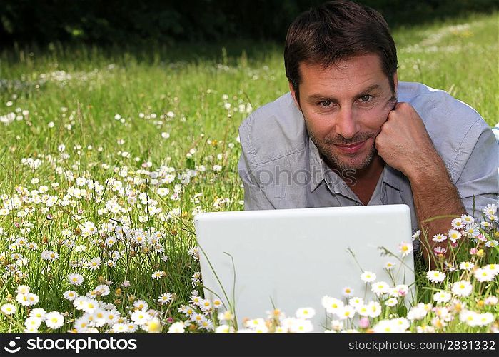 Man working on laptop in the daisies