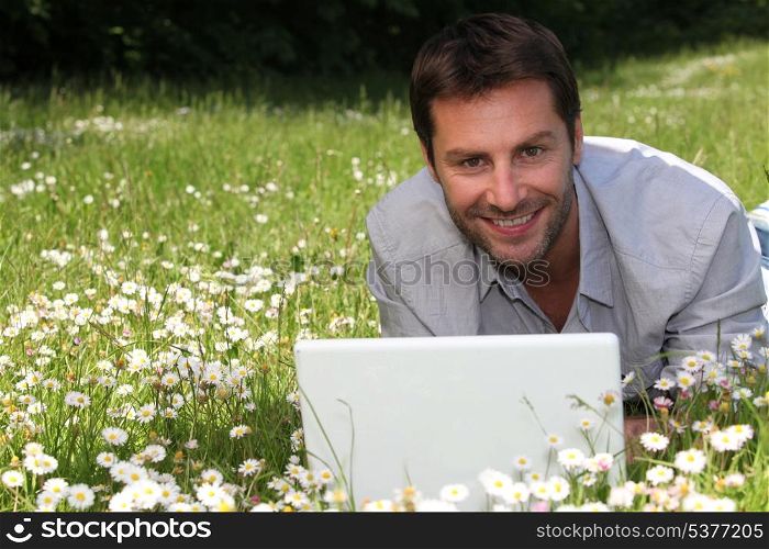 Man working on laptop in the daisies