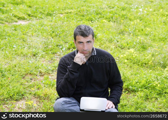 man working on meadow grass with notebook computer black winter sweater