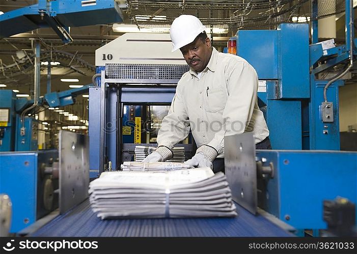 Man working on newspaper production line in newspaper factory