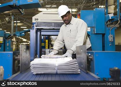 Man working on newspaper production line in newspaper factory