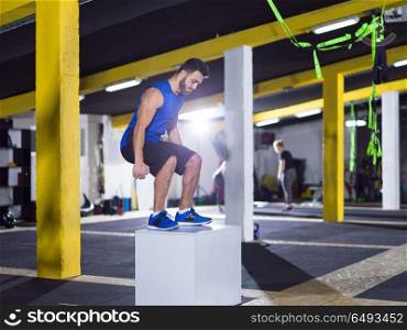man working out jumping on fit box. young athletic man training jumping on fit box at crossfitness gym