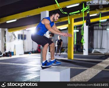 man working out jumping on fit box. young athletic man training jumping on fit box at crossfitness gym
