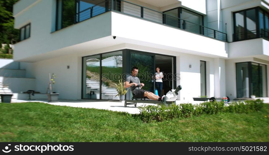 Man Working Out On Row Machine in front of home